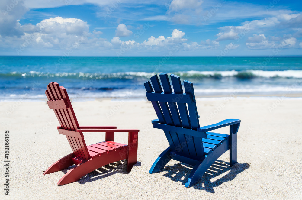 Red and blue beach chairs near ocean