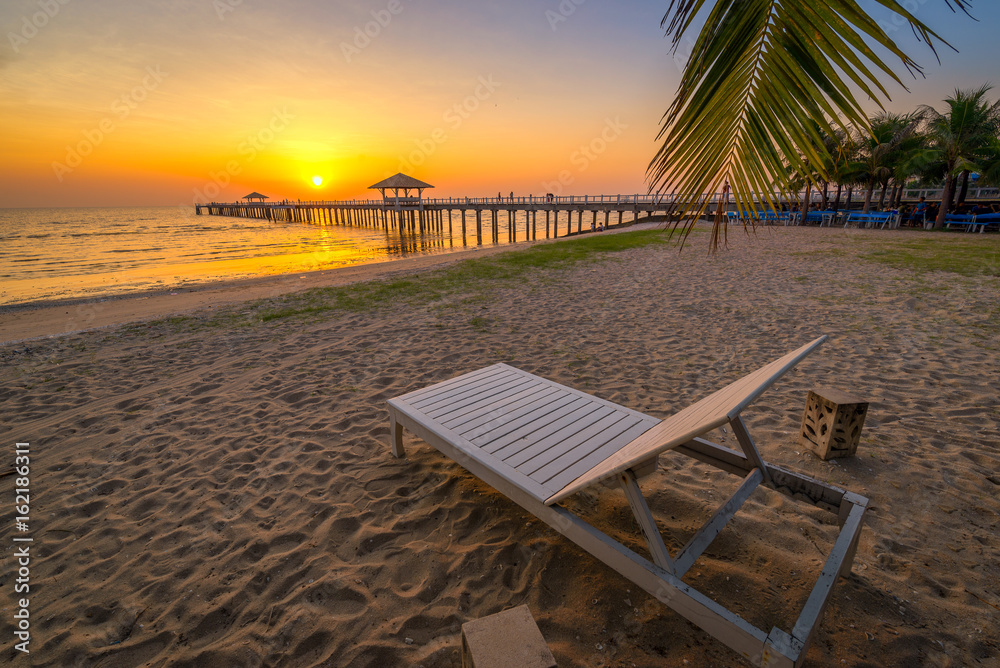 Beach chairs on beach with beautiful beach and tropical sea at sunset.