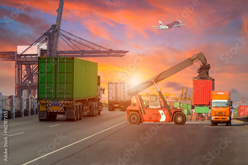 Logistics and transportation of Container Cargo ship and Cargo plane with working crane bridge in shipyard at Twilight sky, logistic import export background and transport industry.