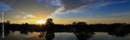 Panorama sunset beautiful colorful landscape and silhouette tree mountain river reflect in sky twilight time © pramot48