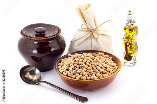 The composition of chick peas in a clay pial next to a clay pot and a copper spoon, photo