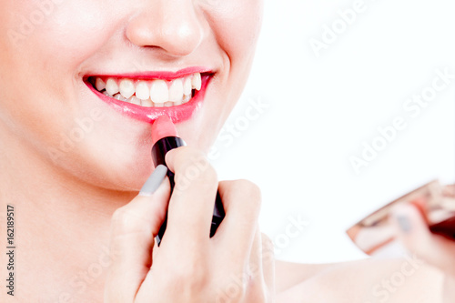 Woman paints lips with lipstick on white background