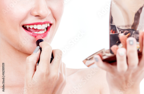 Woman paints lips with lipstick on white background