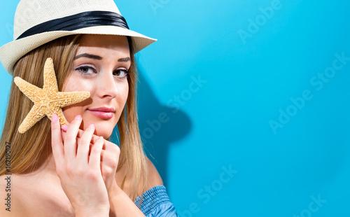 Happy young woman holding a starfish on a blue background