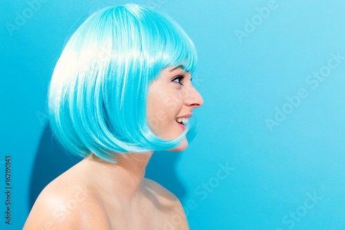 Beautiful woman in a bright blue wig on a blue background