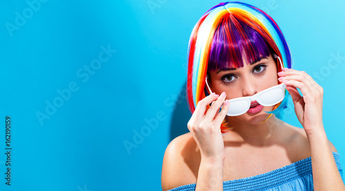 Beautiful woman in a colorful wig on a blue background