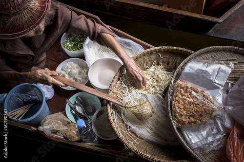 old woman making thai noodle food by sailing in local floating boat market photo