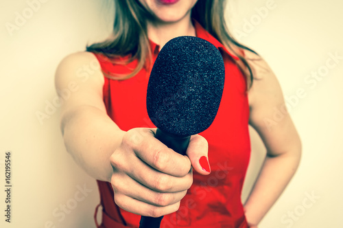 Female reporter with black microphone making interview