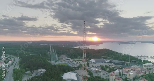 Evening aerial view of ski jumping hills, radio tower and lake in Lahti, Finland, sideways movement