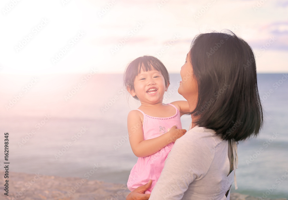 Happy loving family. Mother and her daughter child girl playing and hugging on beach background in the evening. Happy loving family. Mother and her daughter child girl playing and hugging on beach background in the evening.