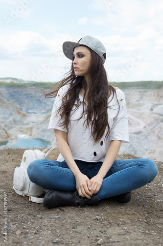 young woman in hat sitting on the mountains