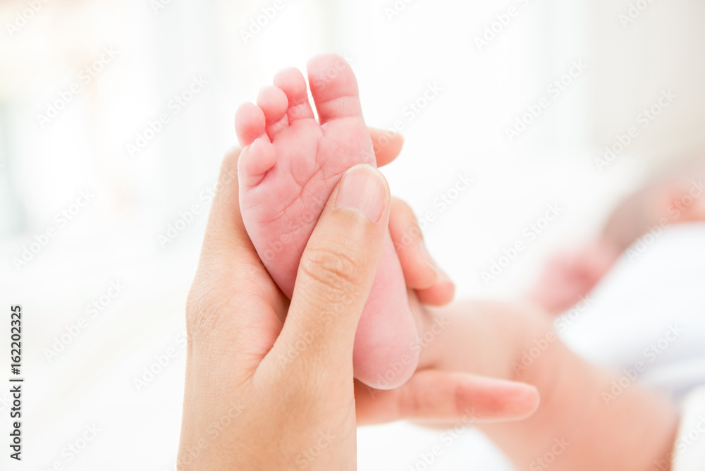 Mother hand holding small baby foot with care Mother hand holding small baby foot with care
