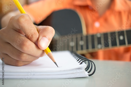 girl student compose song in notebook and playing guitar in school