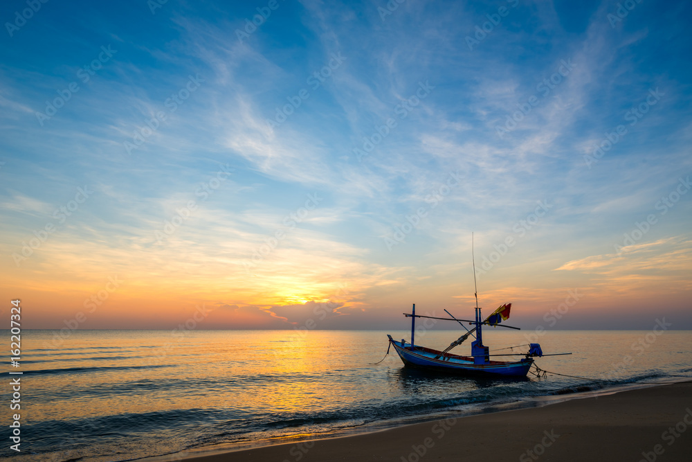 Sunrise on the sea beach with fishing boat
