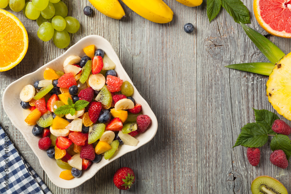 Delicious fruit salad with fresh fruit. Wooden, gray table in the background. Delicious fruit salad with fresh fruit. Wooden, gray table in the background.