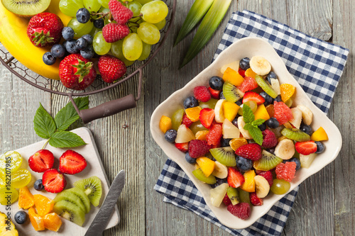 Delicious fruit salad with fresh fruit. Wooden  gray table in the background.
