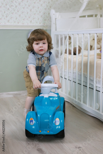 litle boy sit on a toy car