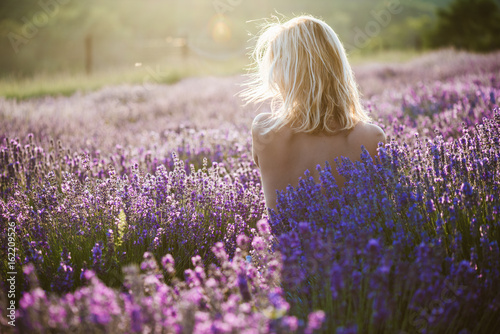 Naked woman posing in lavender field at sunset