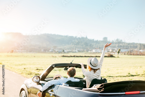 Happy couple drives a convertible in summer on vacation