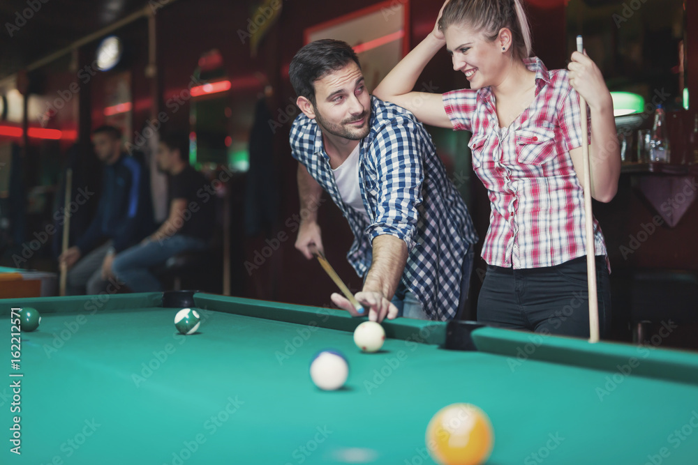 Fototapeta premium Young couple playing together pool in bar
