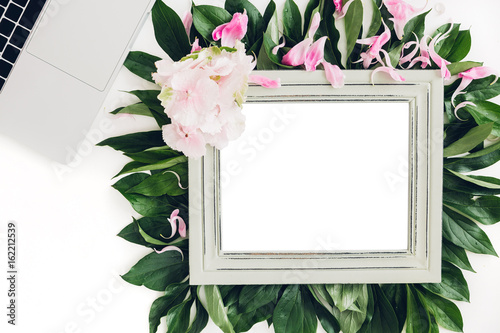 wooden frame decorated with flowers and leaves, laptop and phone. empty space for text