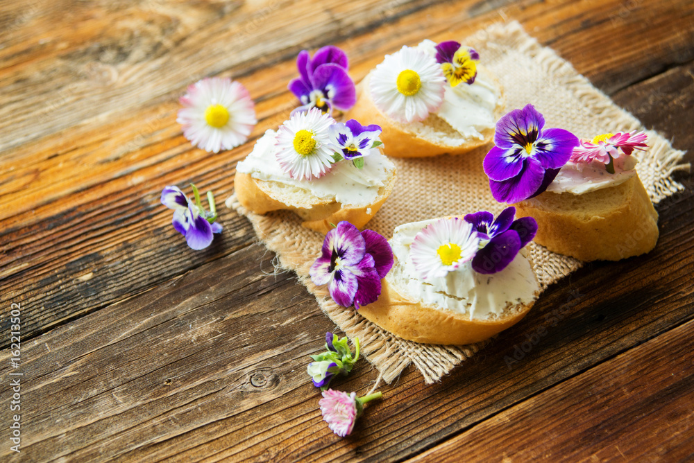 Sandwich with herb and edible flowers butter on marble cutting board. Healthy food.