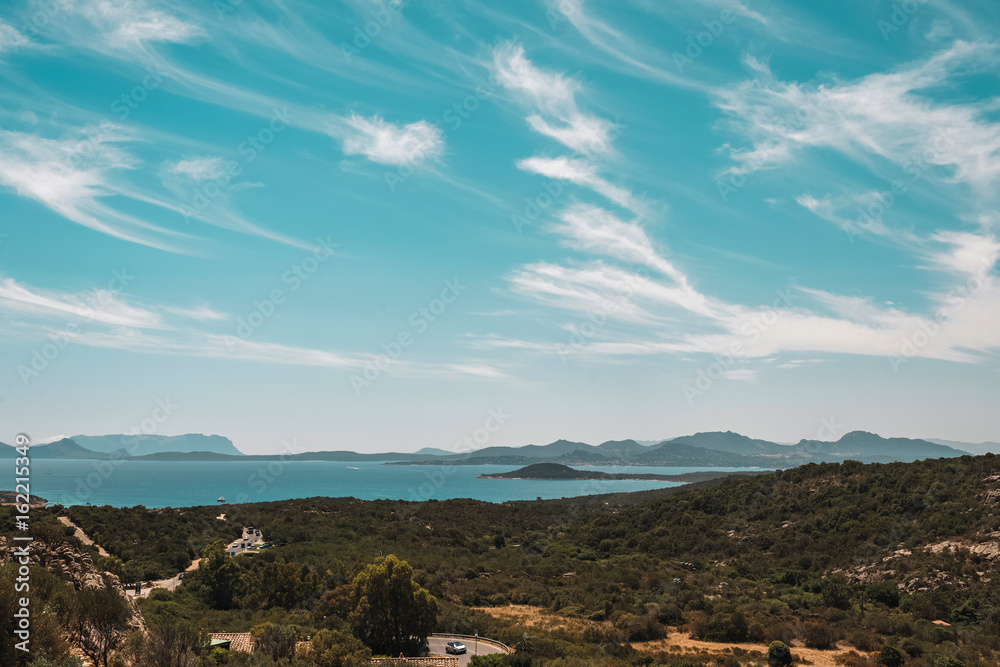Summer mountain landscape with lake and road far away under blue cloudy sky. Sardinia. Italy.