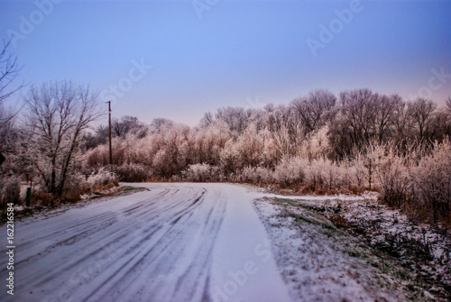 A snow covered gravel road in a rural area
