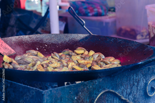 Potato preparing in a big black cauldron photo