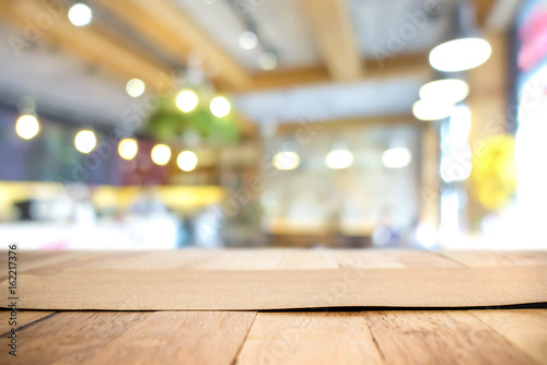 Brown paper on wood table top in blur restaurant interior background