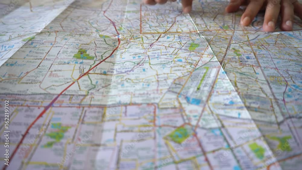 Dolly shot of man's hand drawing on map by finger
