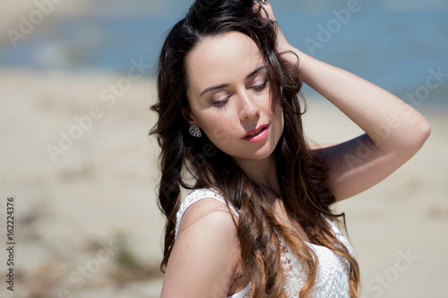 Young beautiful brunette woman in white dress on the seashore. portrait with closed eyes © Ulia Koltyrina