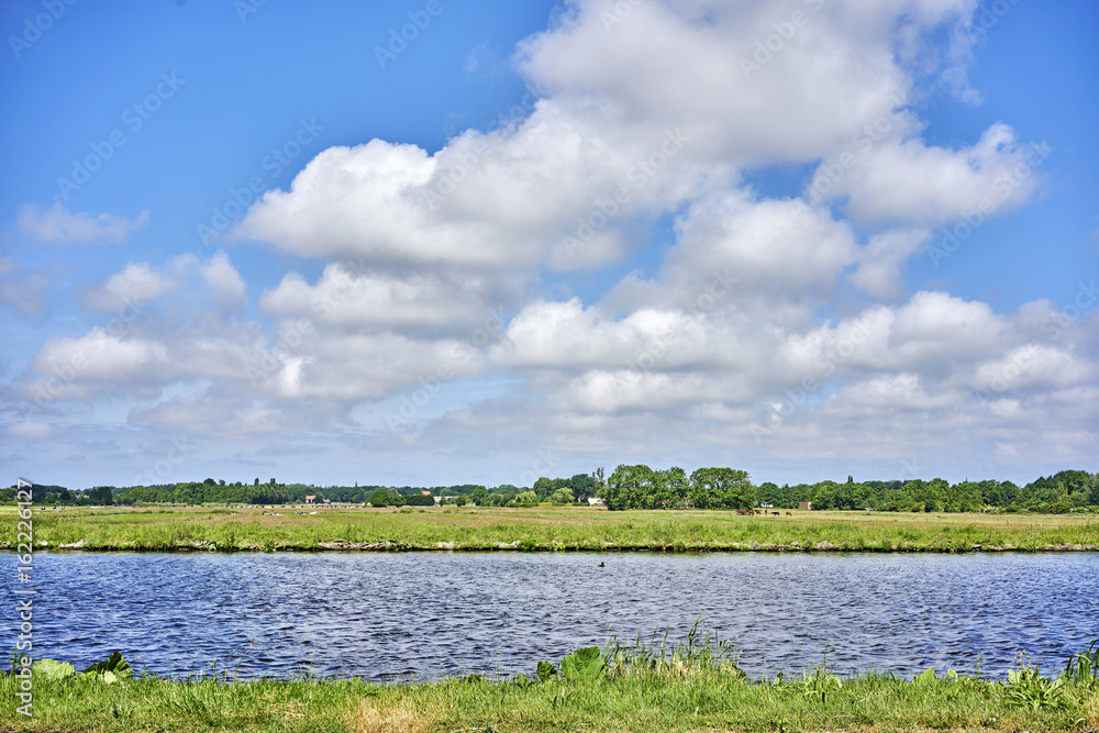 Fototapeta premium grassland with water canal against sky