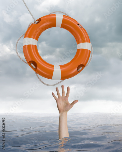 Man is drowning in ocean and is catching life buoy.