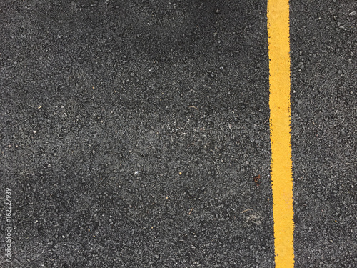 Yellow paint line on black asphalt road surface texture. space transportation background