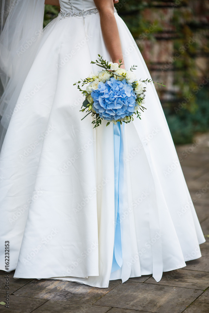 Bride holds hand with blue wedding bouquet down Bride holds hand with blue wedding bouquet down