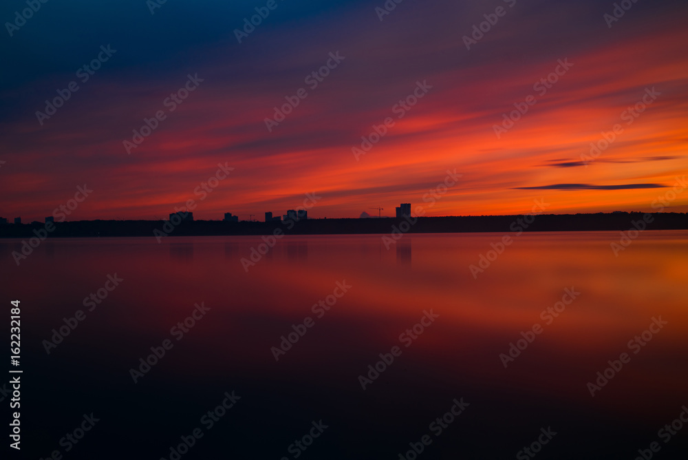 Orange and red sunset at coast of the lake