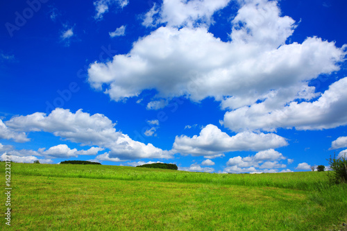 Blue sky with clouds and green field.