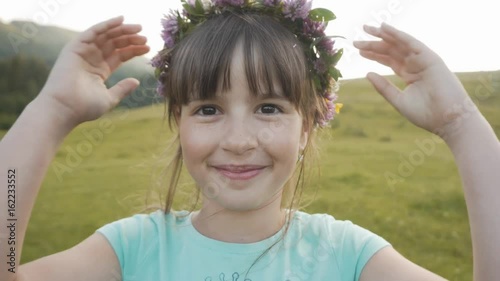 Pportrait of cute young smiling girl with flowers wreath on her head