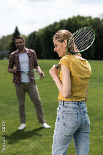 happy caucasian couple playing badminton on green field