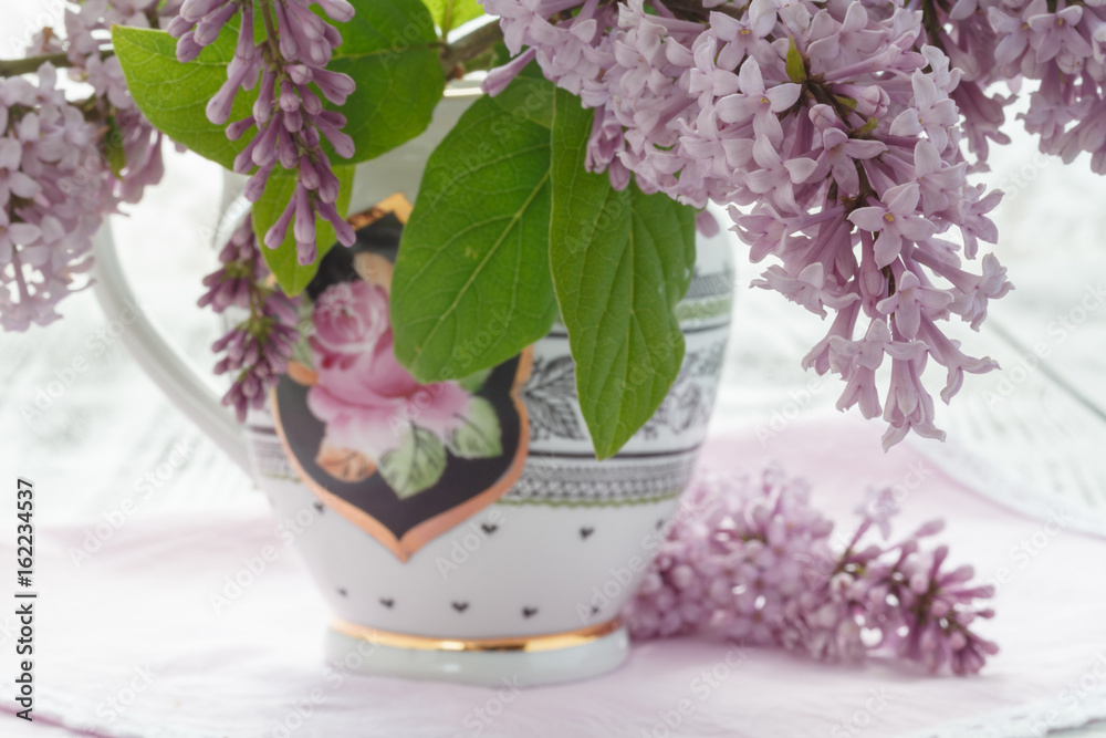 Fototapeta premium Vase with a bouquet of purple lilac spring flowers on vintage textured background