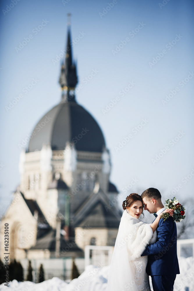 Obraz premium Groom hugs tender bride in fur coat standing outside