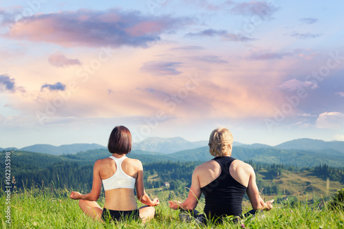 Beautiful young woman and man doing yoga exercise