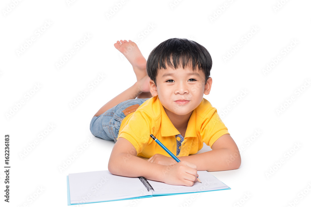 Schoolboy lying down and writing in notebook. Schoolboy lying down and writing in notebook.