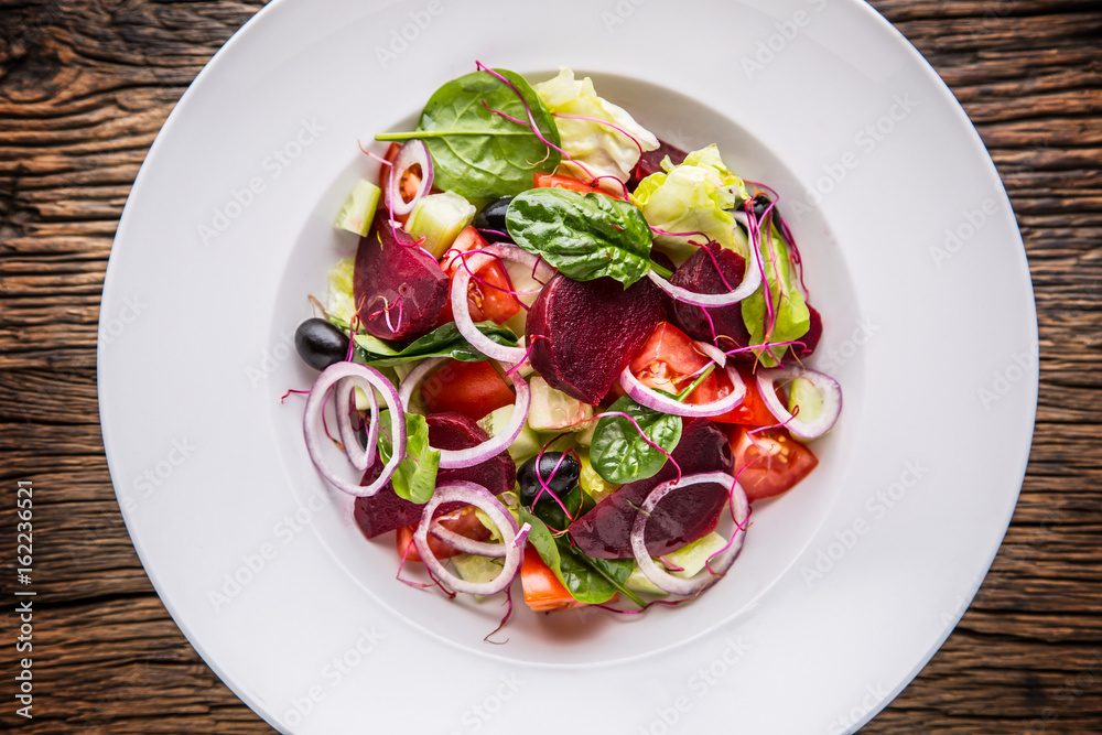 Vegetable salad. Plate of salad with vegetables on rustic oak table. Assortment of ingredients of vegetable salad. Vegetable salad. Plate of salad with vegetables on rustic oak table. Assortment of ingredients of vegetable salad.