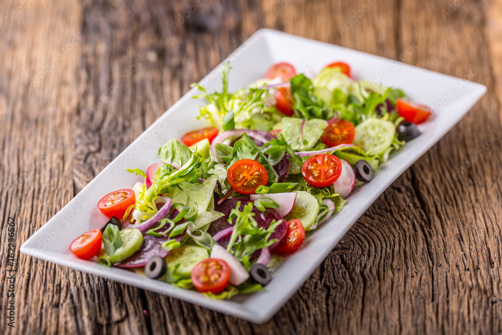 Vegetable salad. Plate of salad with vegetables on rustic oak table. Assortment of ingredients of vegetable salad. Vegetable salad. Plate of salad with vegetables on rustic oak table. Assortment of ingredients of vegetable salad.