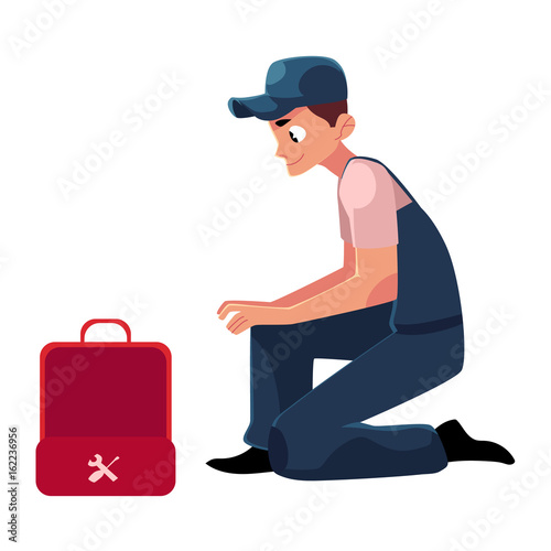 Smiling plumbing specialist, plumber sitting with wrench and open toolbox, cartoon vector illustration isolated on white background. Side view portrait of plumber, plumbing specialist with a toolbox