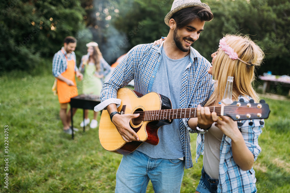 Handsome man playing guitar to his girlfriend in nature