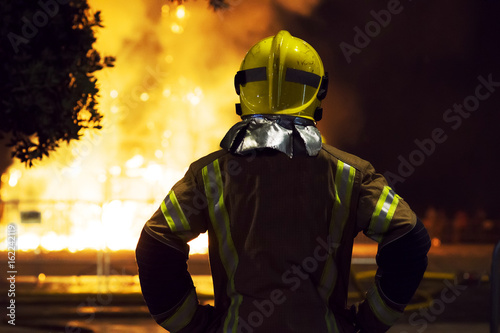 firefighter watching a fire on the city street while trying to put out the flames 