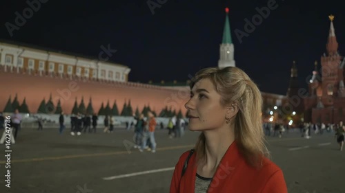 The girl walks and admires the night red square and the Kremlin in Moscow. photo